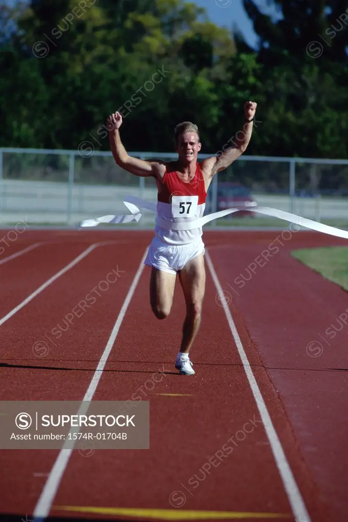 Portrait of a male runner crossing the finishing line with his arms raised