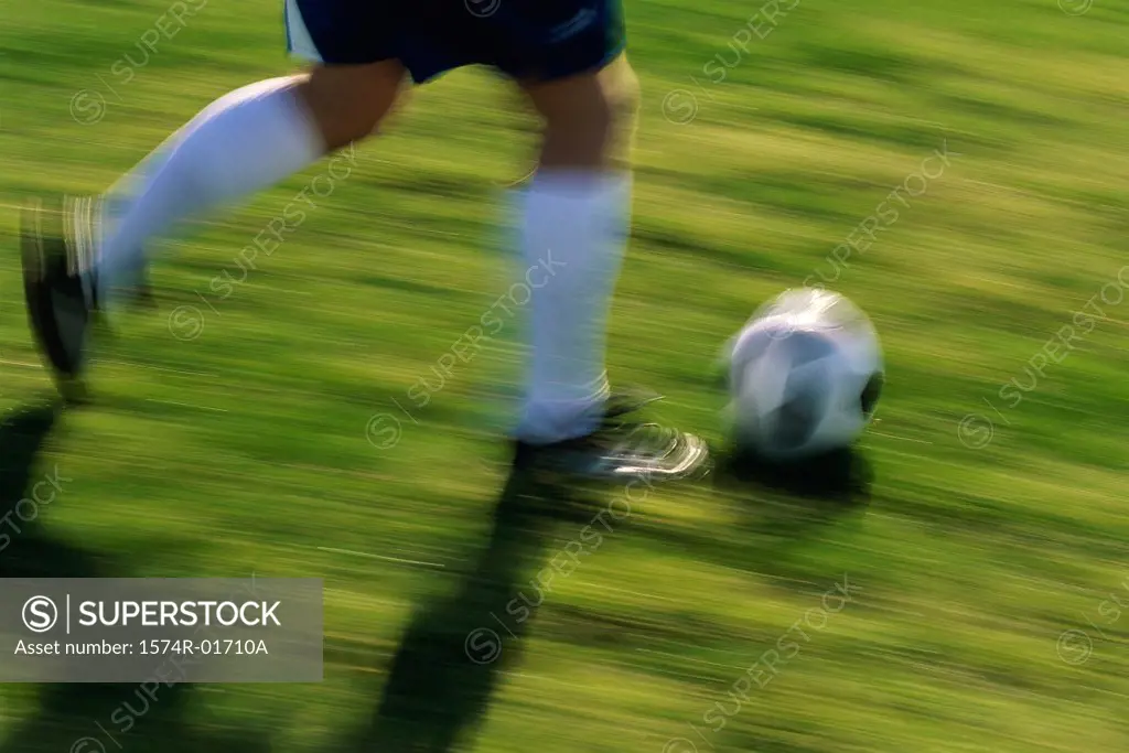 Low section view of a soccer player running with the ball