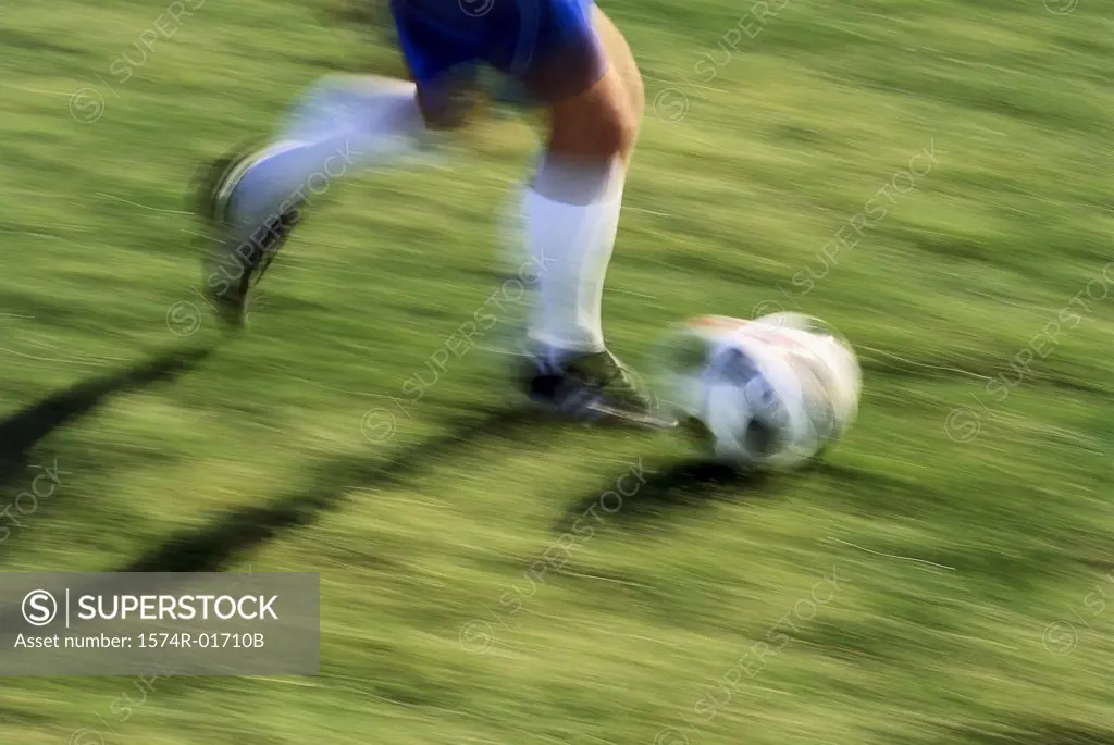 Low section view of a soccer player running with the ball