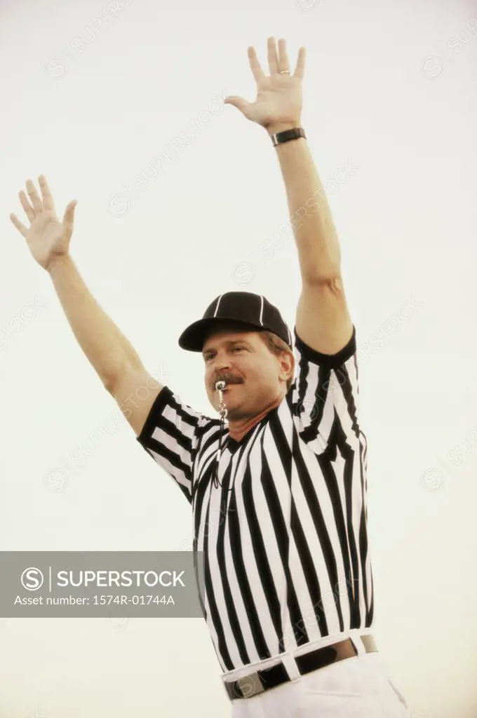 Football referee whistling with his arms raised