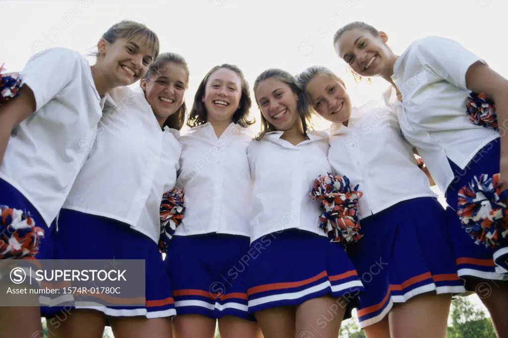 Portrait of teenage girls in uniform with pom-poms