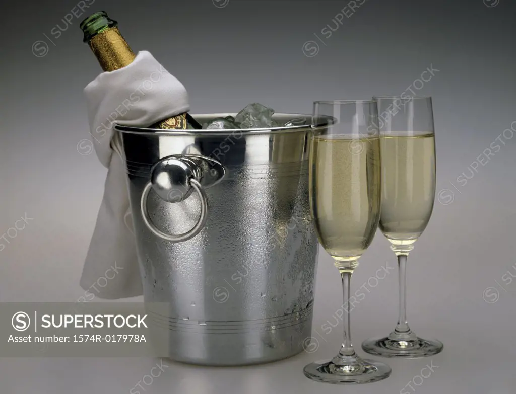 Close-up of two champagne flutes with an ice bucket