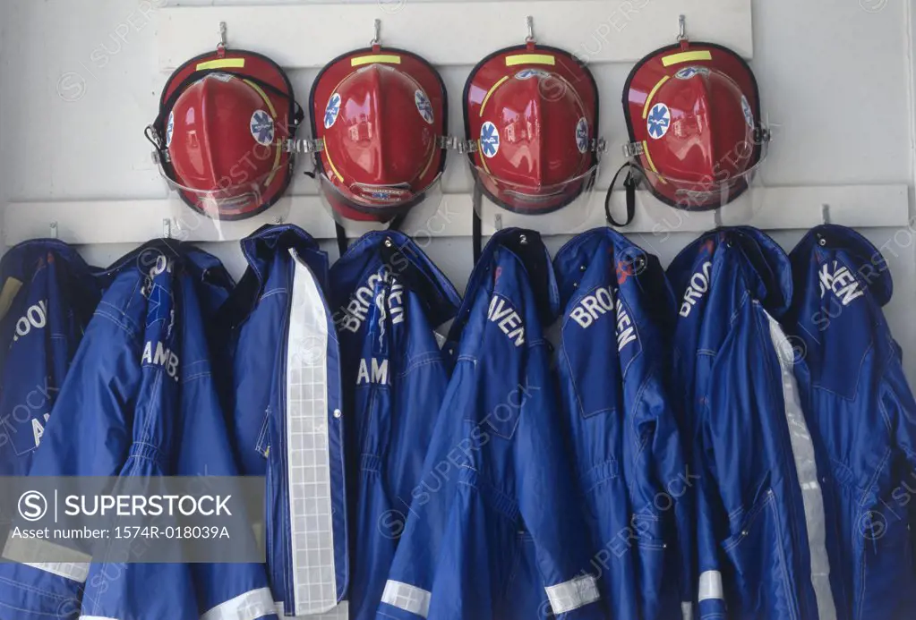 Close-up of fire fighter's helmets and fire protective suits hanging on hooks