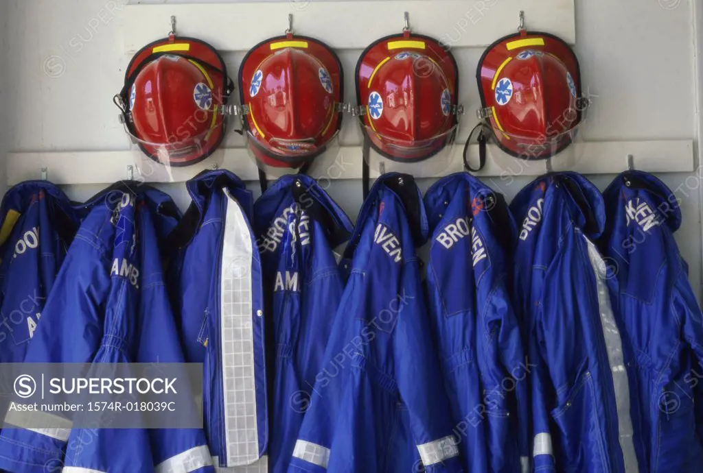 Close-up of fire fighter's helmet and fire protective suits hanging on hooks