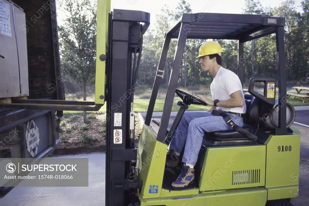 Side profile of a young man driving a forklift