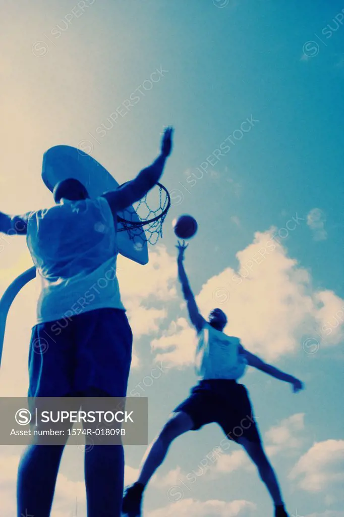 Low angle view of two young men playing basketball