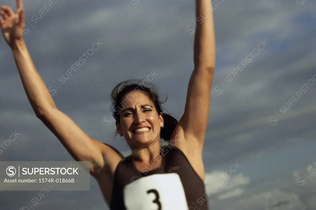Low angle view of a female athlete with arms raised