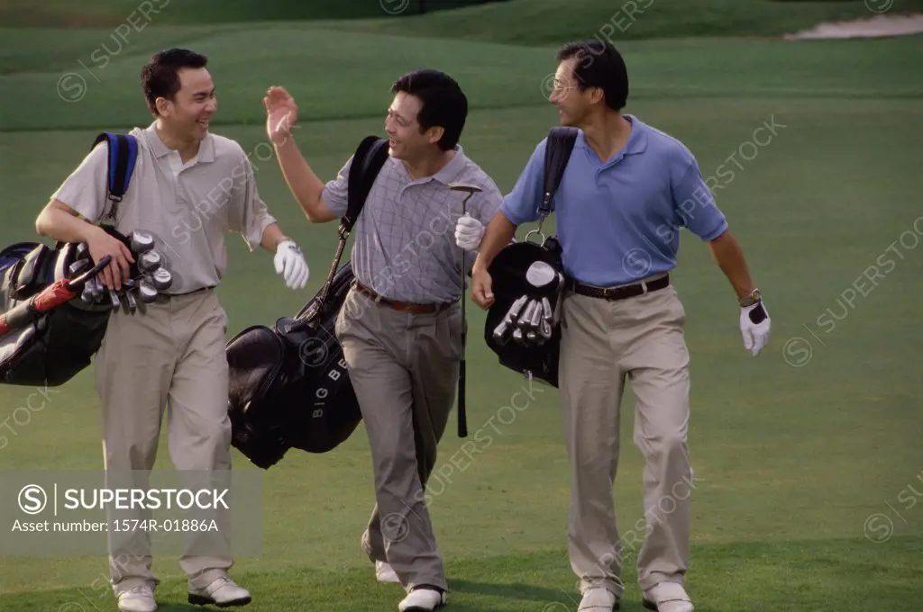 Three men carrying golf bags at a golf course