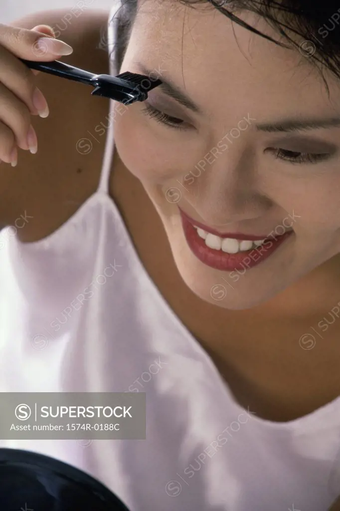 Young woman applying make-up in a mirror