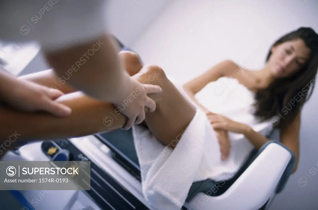 Low angle view of a person's hands massaging a young woman's leg