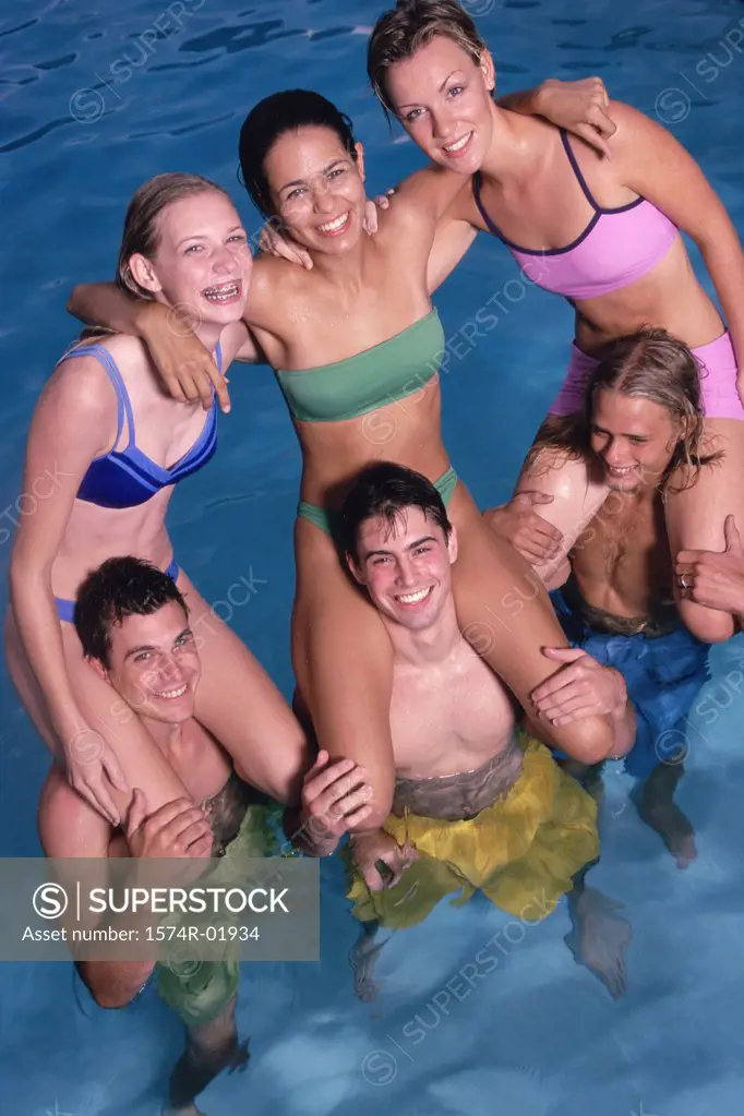 Group of teenage girls sitting on teenage boys shoulders in the water