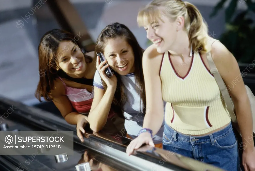 Three teenage girls standing on an escalator
