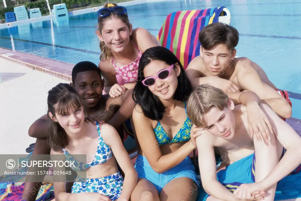 Portrait of a group of teenagers sitting beside a swimming pool