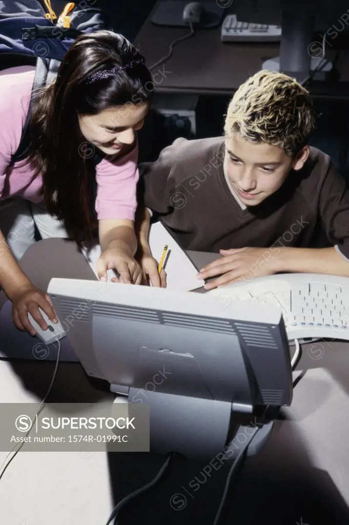 Teenage boy and a teenage girl in front of a computer monitor