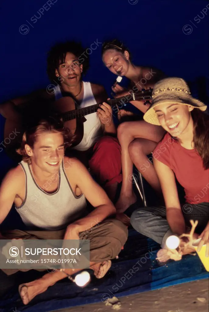Two young couples sitting by a bonfire on the beach