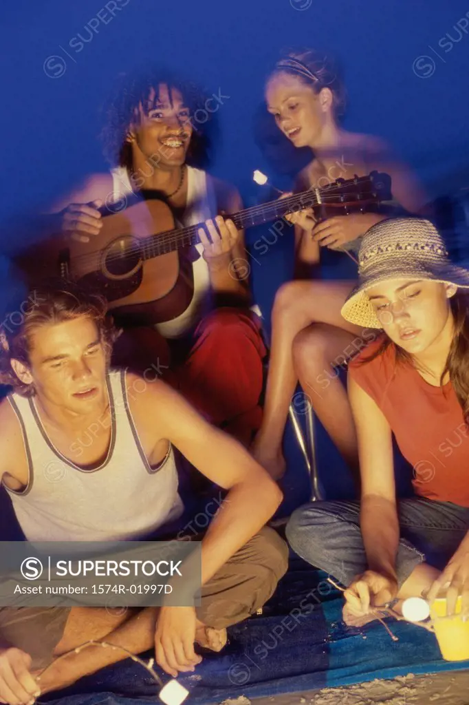 Two young couples sitting by a campfire toasting marshmallows