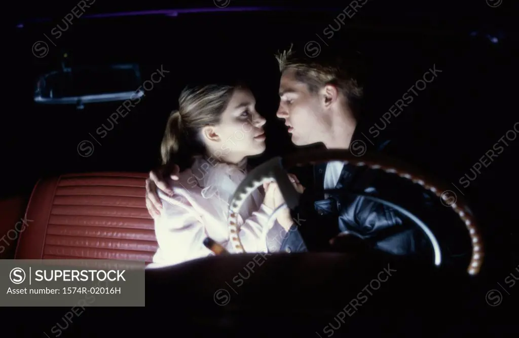 Teenage couple sitting in a car looking at each other