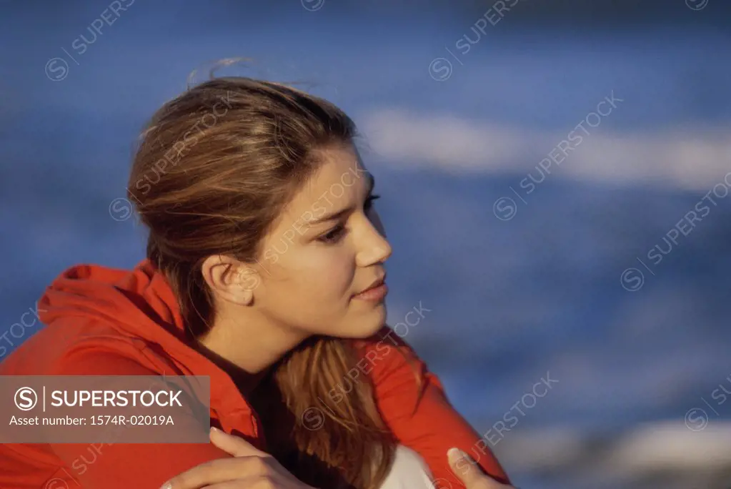 Side profile of a teenage girl sitting at the beach