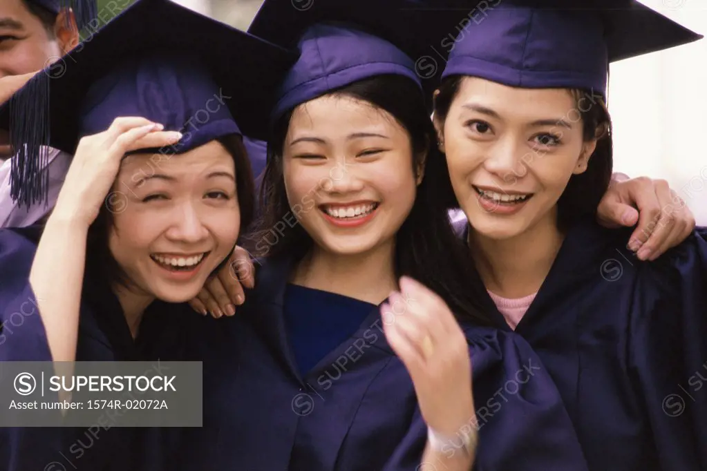 Portrait of three young women in graduation outfits