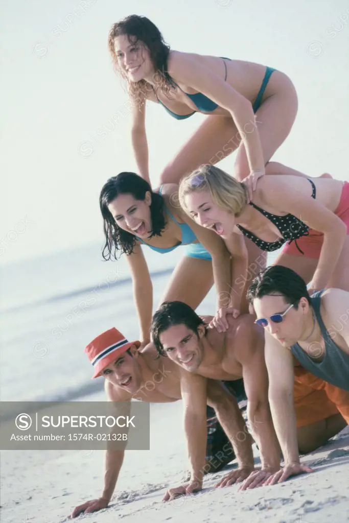 Group of young people making a human pyramid on the beach