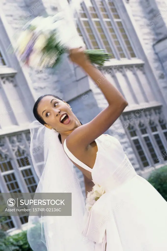 Low angle view of a newlywed young woman tossing the bouquet