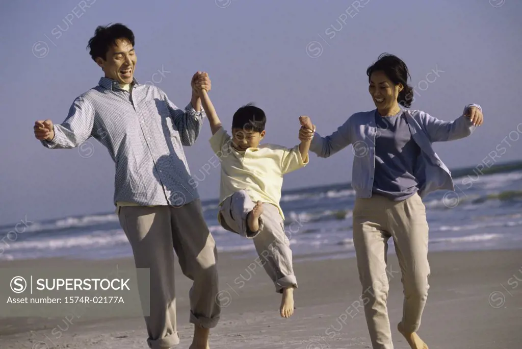 Parents carrying their son on the beach