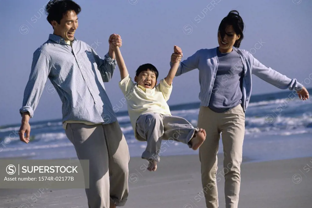 Parents carrying their son on the beach