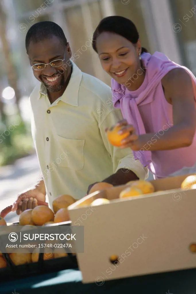 Young couple picking oranges from a shop in a market