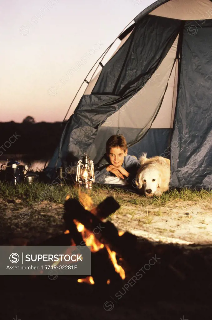 Boy camping in a tent with his dog