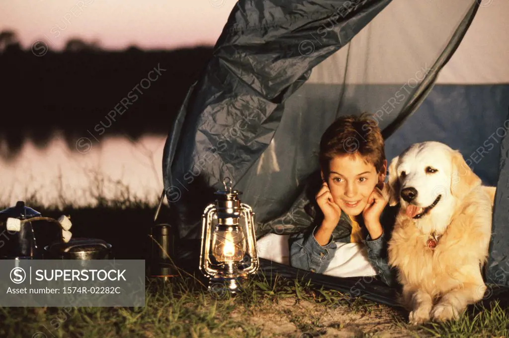 Boy lying in a tent with his dog