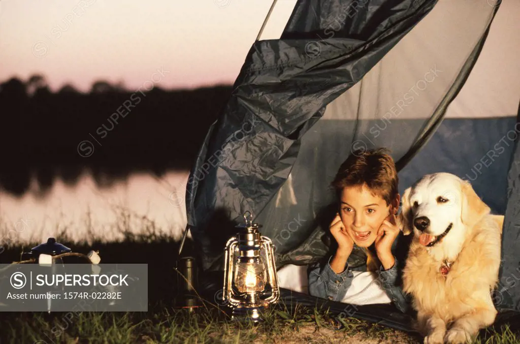 Boy lying in a tent with his dog