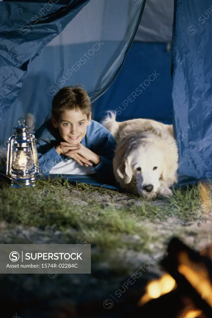 Boy camping in a tent with his dog