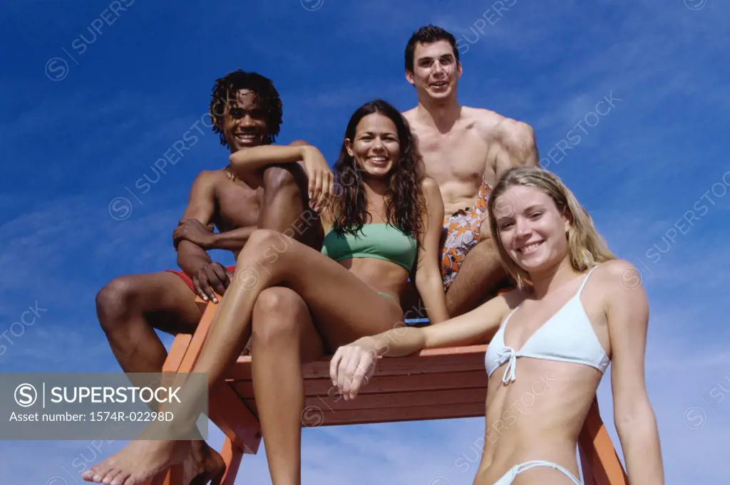 Portrait of two teenage couples sitting on a lifeguard tower