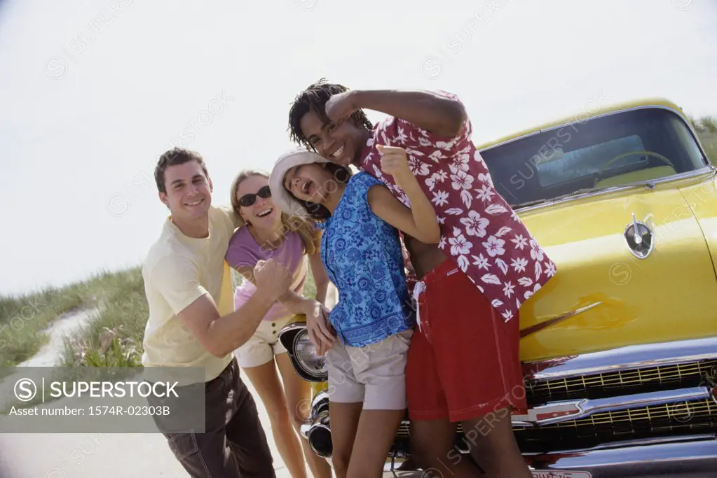 Portrait of two teenage couples standing beside a car