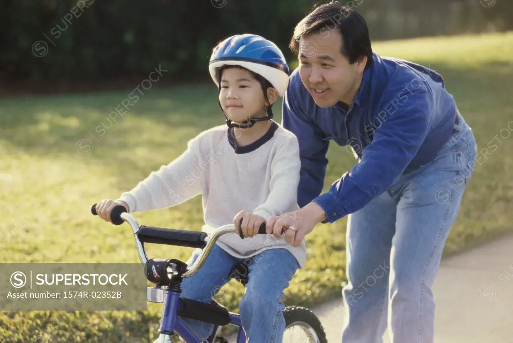 Father helping his son ride a bicycle