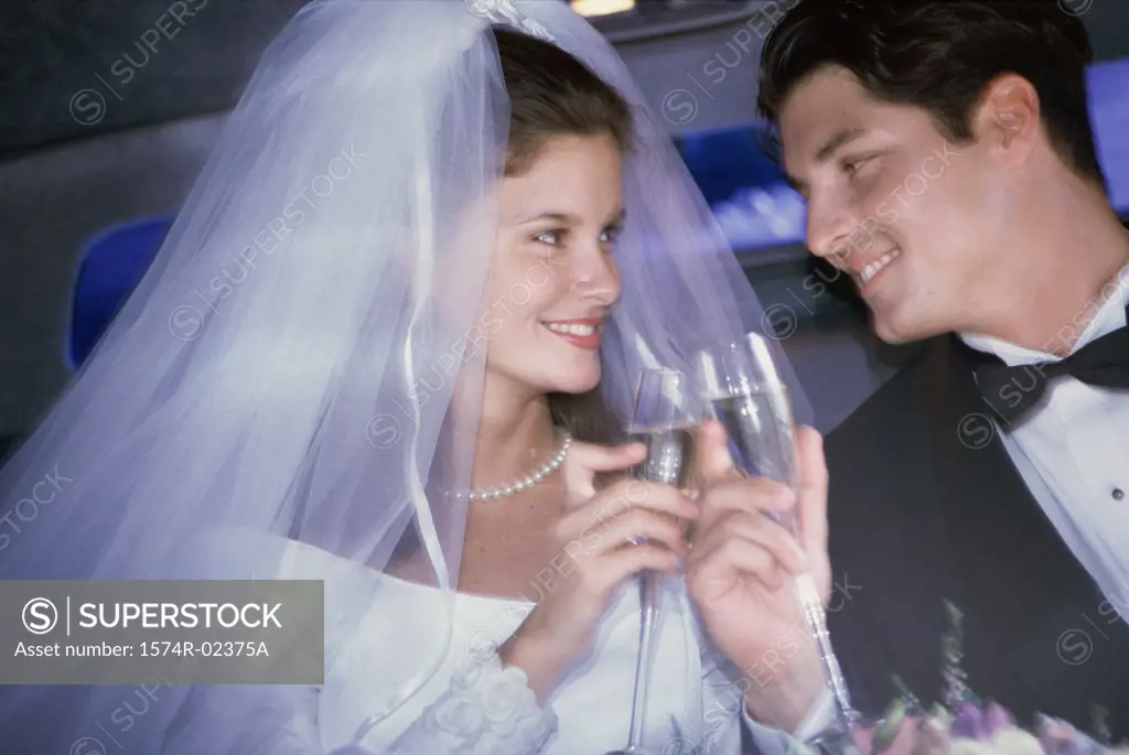 Newlywed couple toasting with champagne glasses in a car