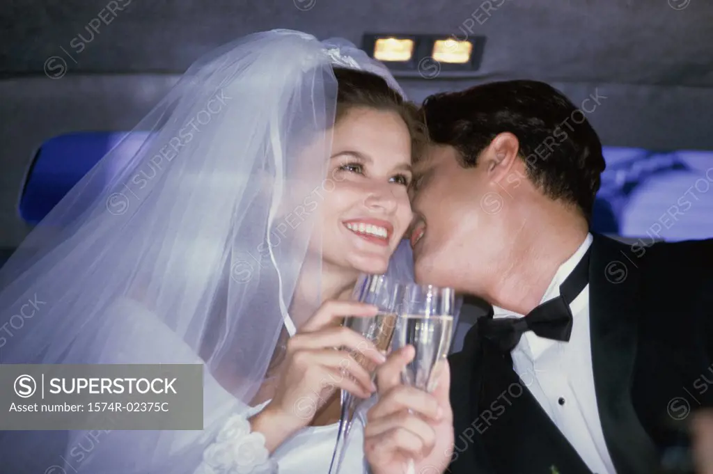 Newlywed couple toasting with champagne glasses in a car