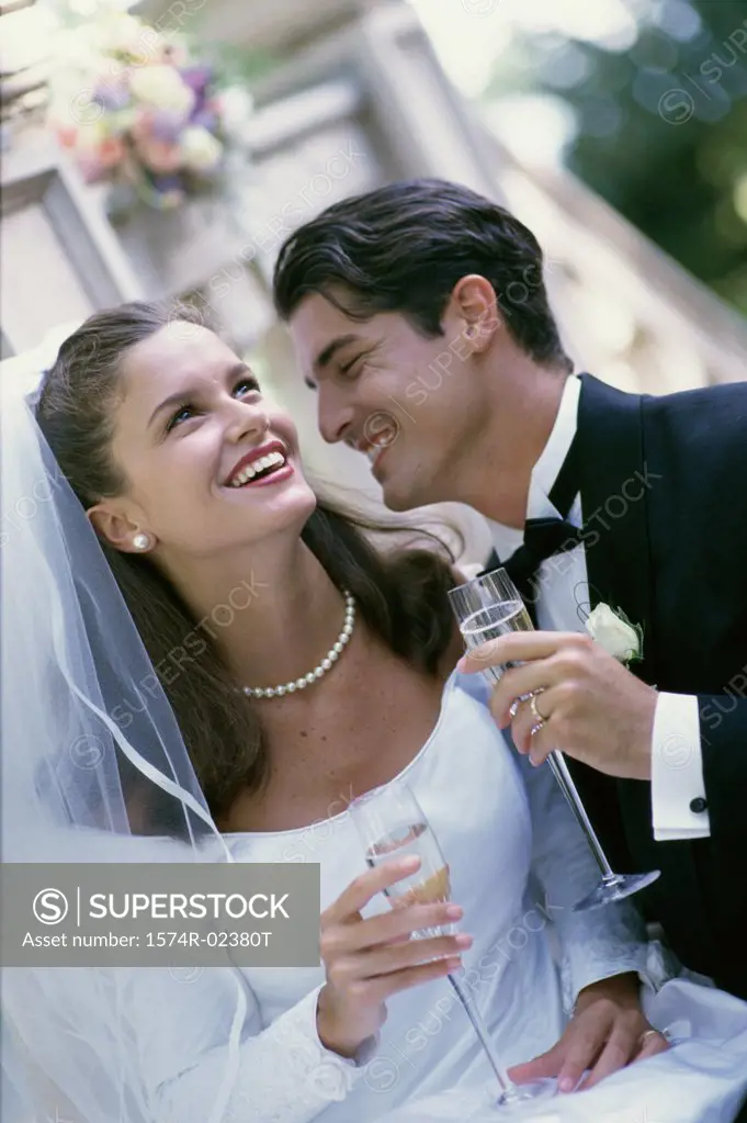 Newlywed couple smiling while holding glasses of champagne