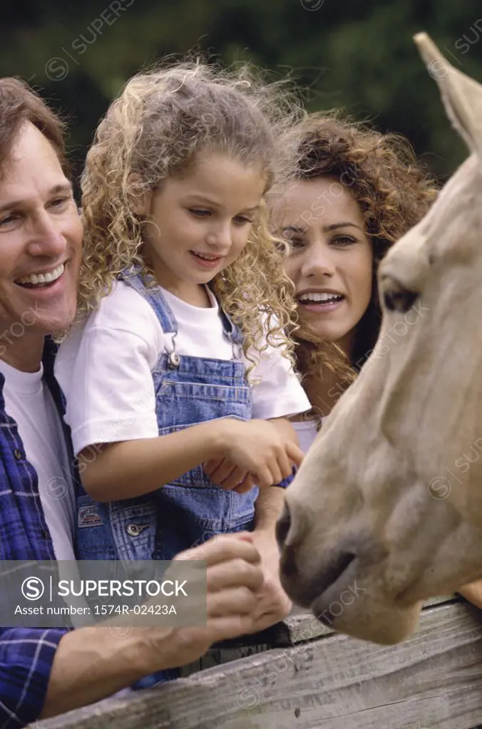 Parents with their daughter standing in front of a horse