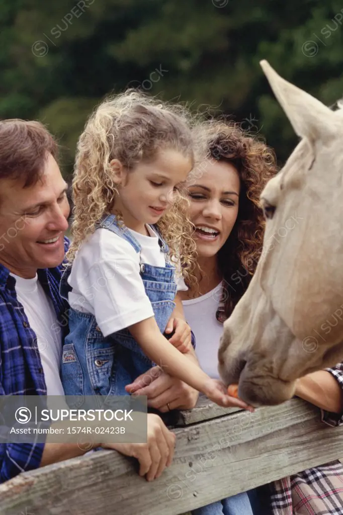 Parents with their daughter standing in front of a horse