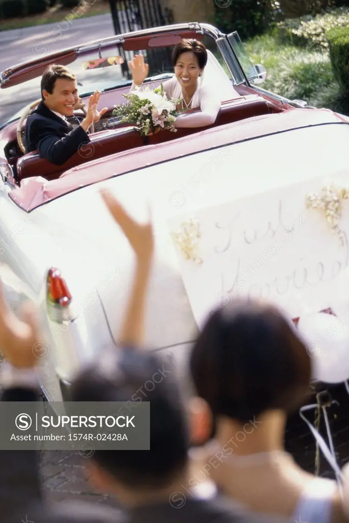 High angle view of a newlywed couple waving from a convertible car