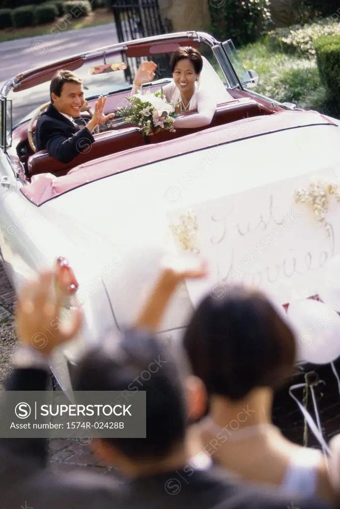 High angle view of a newlywed couple waving from a convertible car