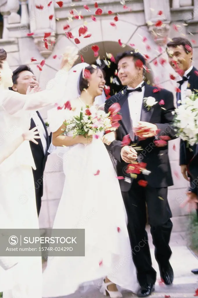 Flower petals being thrown on a bride and groom
