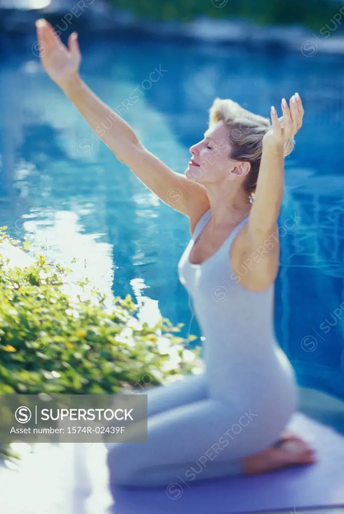 Mid adult woman practicing yoga poolside