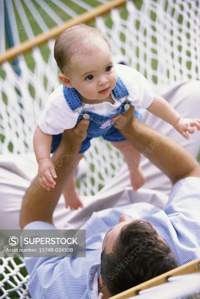 Father lying in a hammock playing with his baby boy