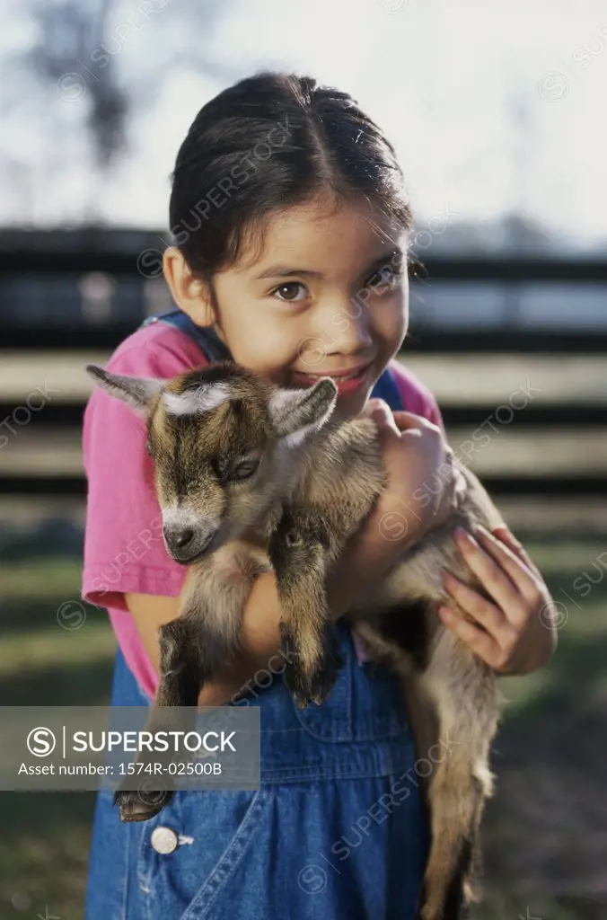 Portrait of a girl holding a kid goat in her arms