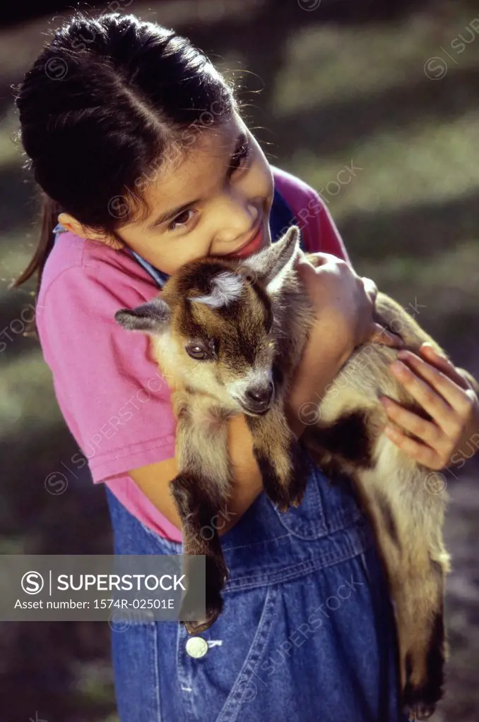 High angle view of a girl holding a kid goat in her arms