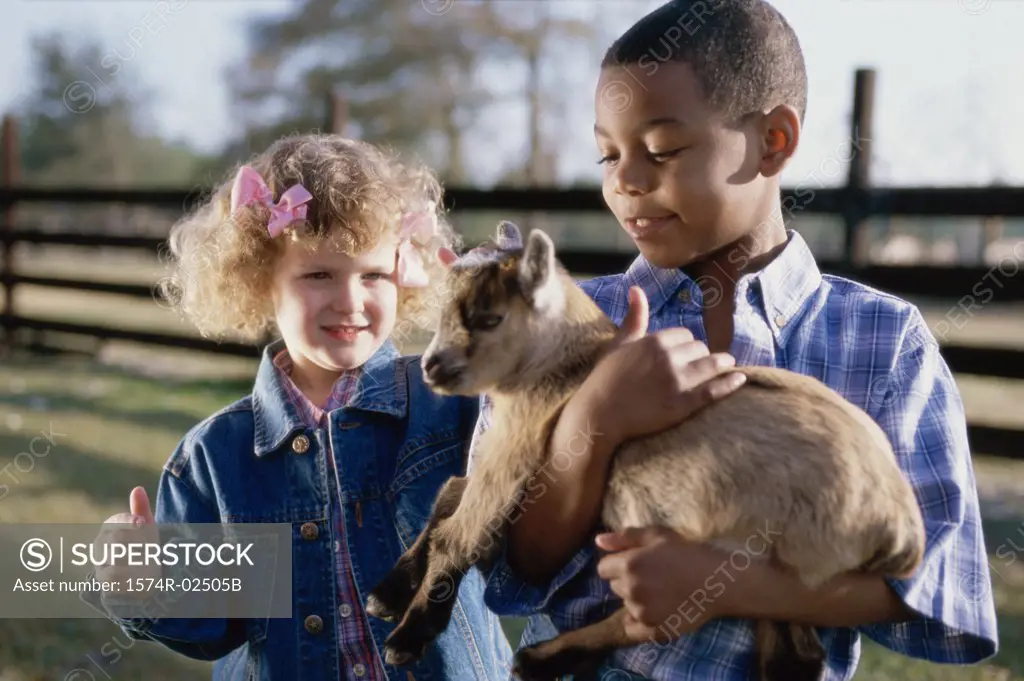 Boy standing with a girl holding a goat