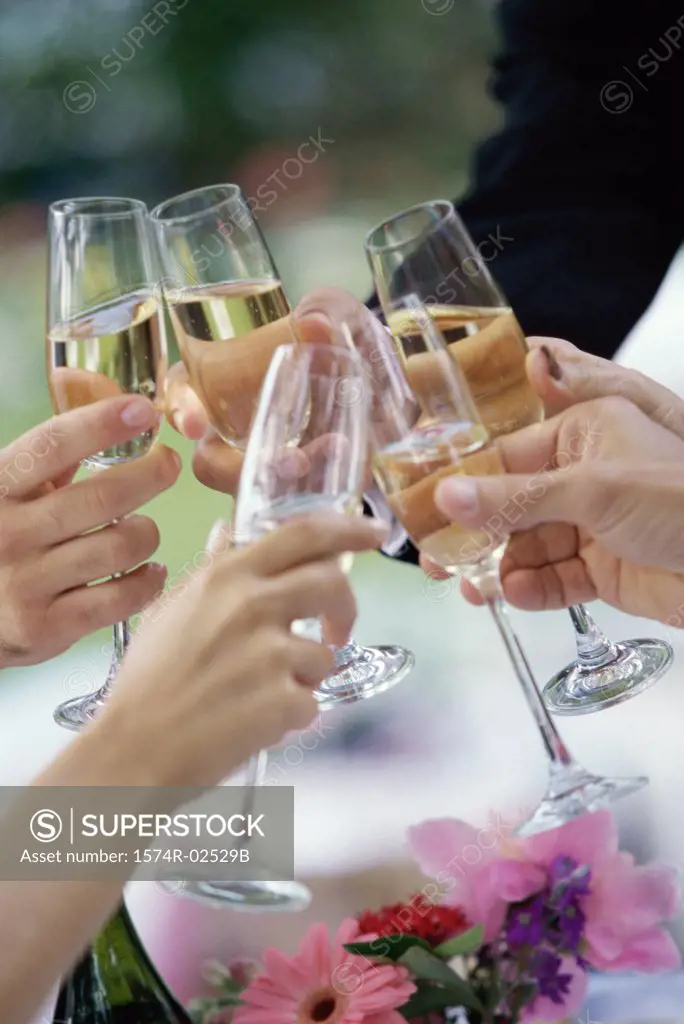 Close-up of peoples hands toasting with glasses of champagne
