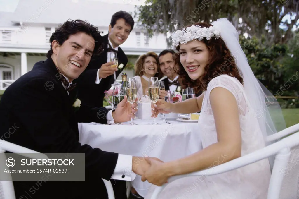 Portrait of a newlywed couple and their friends toasting with champagne glasses